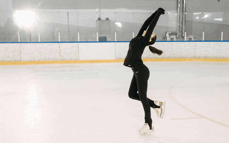 A figure skater performs a jump, her body soaring gracefully through the air, while her flowing costume creates a beautiful and dynamic visual display